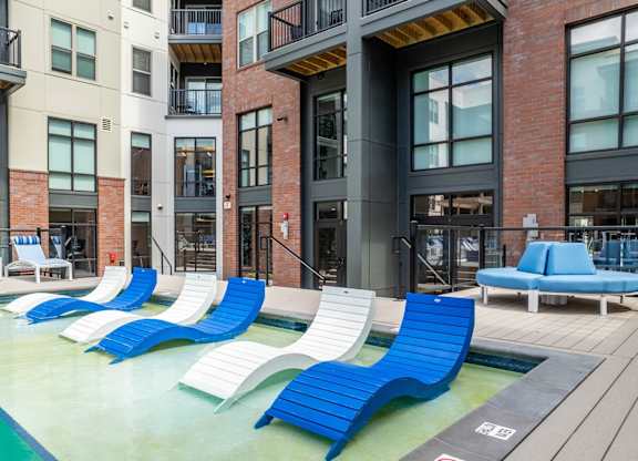 A pool area with blue and white lounge chairs. at Elevate Apartments, Madison, 53718