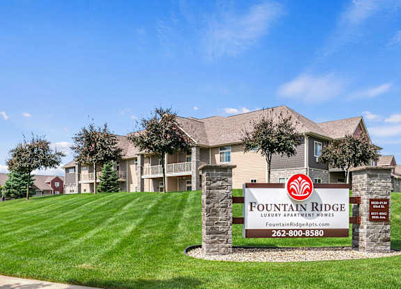 A sign for Fountain Ridge Lounge Apartment Homes is in front of a building.