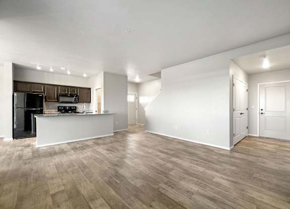 A spacious kitchen with wooden floors and white walls.