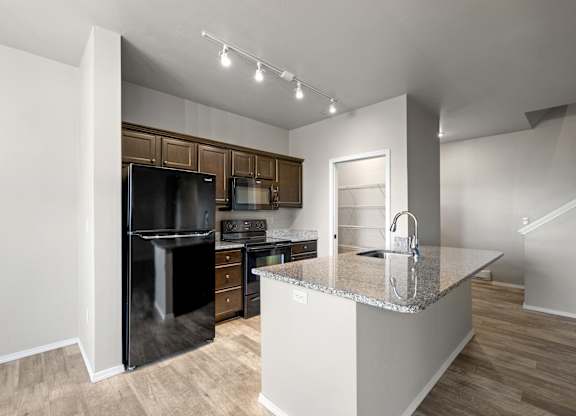 A kitchen with a black fridge and stove top oven.