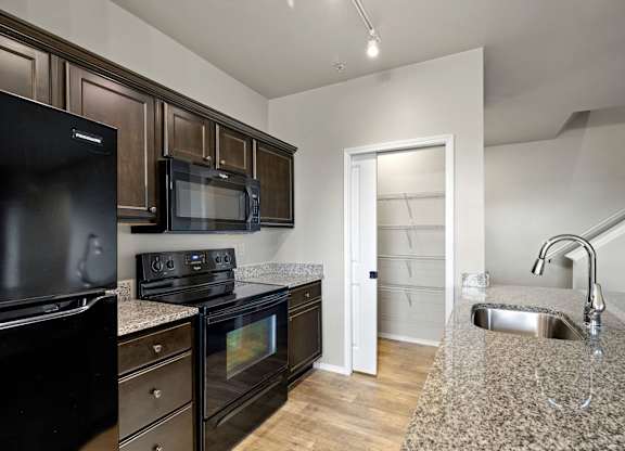 A kitchen with black appliances and wooden cabinets.