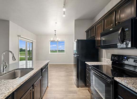 A kitchen with black appliances and a view of the outdoors through the window.