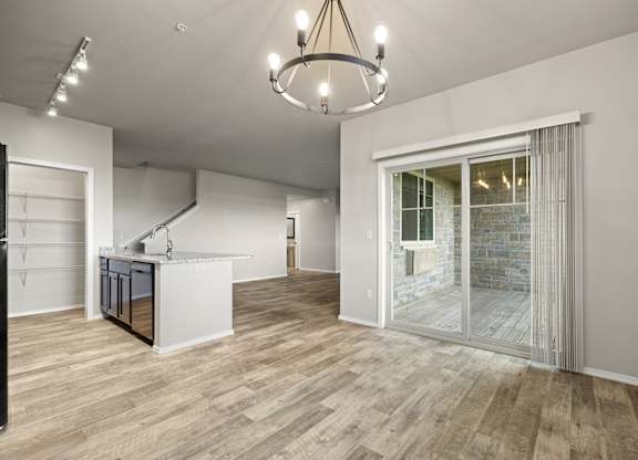 A modern kitchen with a wooden floor and a chandelier.