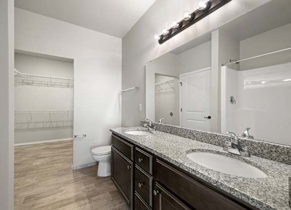 A bathroom with a toilet, sink, and mirror.
