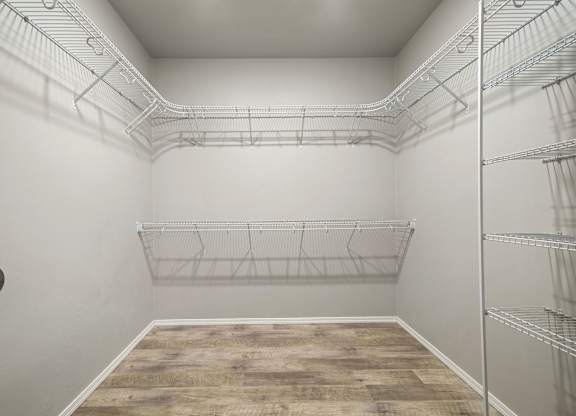 Empty walk-in closet with shelves and a wooden floor.