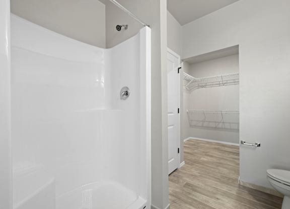 A white bathroom with a toilet and a walk in shower.