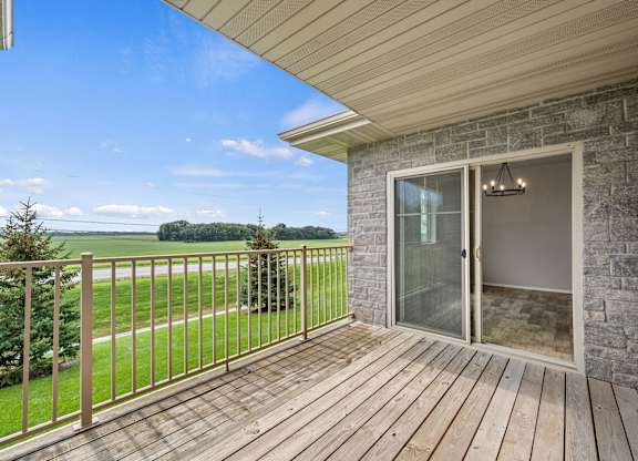 A balcony with a glass door and a wooden floor.