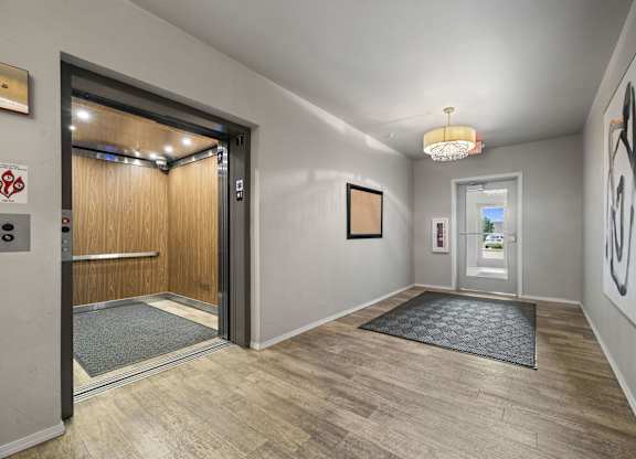 A hallway with a wooden floor and a glass door leading to another room.