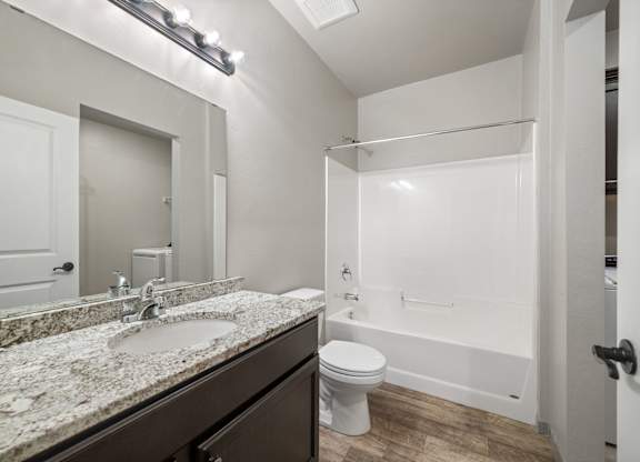 A bathroom with a marble countertop and white fixtures.