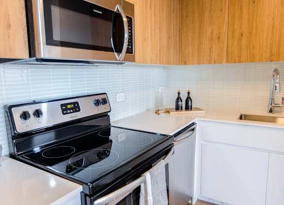 a small kitchen with a stove and a microwave at The Kent, Chicago, IL, 60614