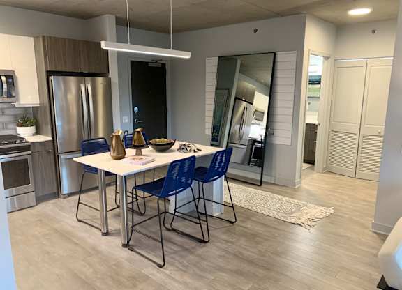 a kitchen and dining room with stainless steel appliances and a table with blue chairs  at Residences at Addison Clark Apartments, Chicago, IL, 60613