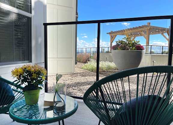 a balcony with a glass table and chairs and a patio at 42 Hundred On The Lake, St Francis, 53235