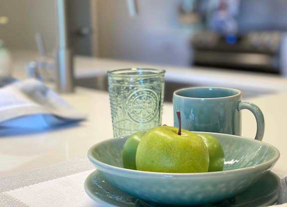 a green apple sitting in a bowl on a table at 42 Hundred On The Lake, St Francis, WI, 53235
