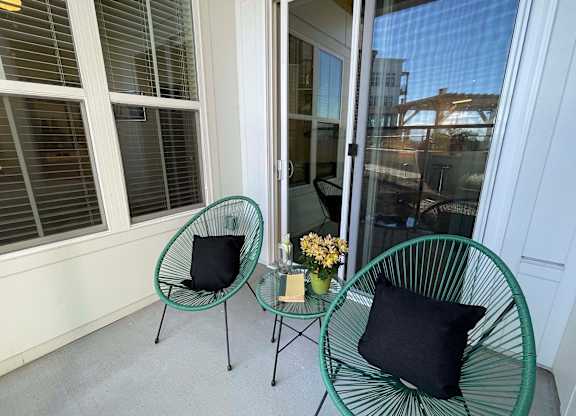 a balcony with two green chairs and a table with a black pillow at 42 Hundred On The Lake, Wisconsin