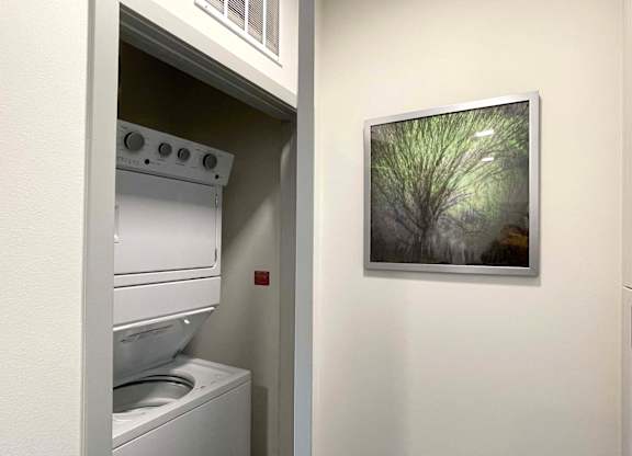 a laundry room with a washing machine and a painting of a tree at 42 Hundred On The Lake, St Francis, 53235