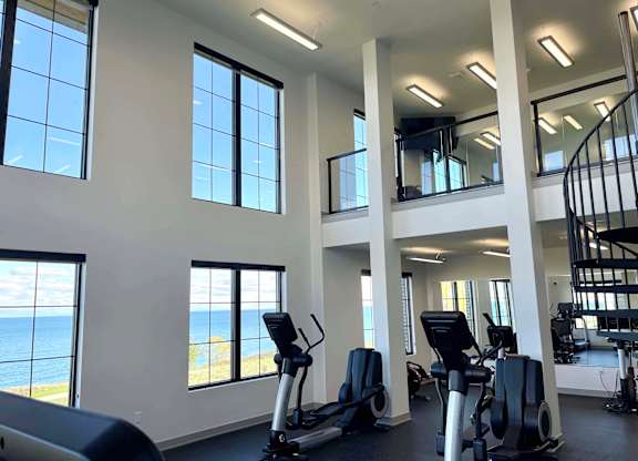 a gym with cardio equipment and windows overlooking the lake at 42 Hundred On The Lake, Wisconsin, 53235