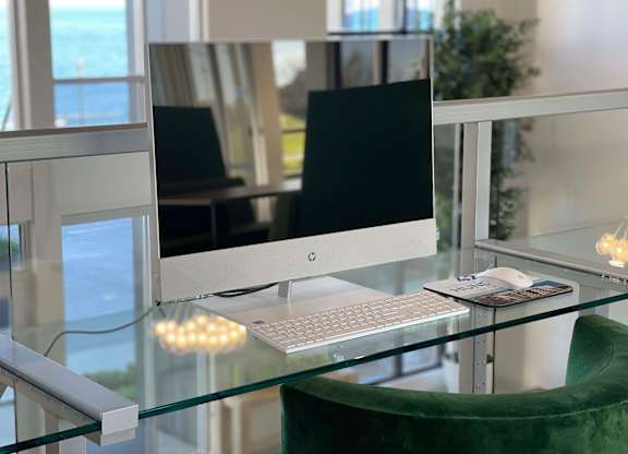 a computer on a glass desk with a keyboard and mouse at 42 Hundred On The Lake, St Francis