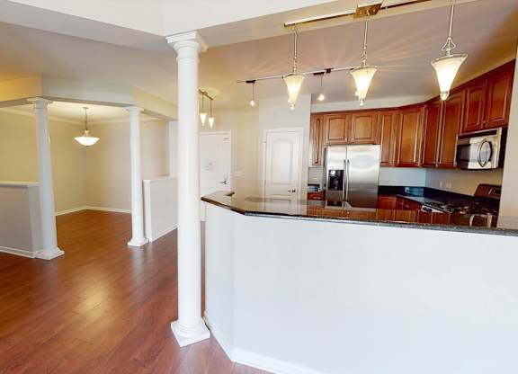 A kitchen with white countertops and wooden floors.
