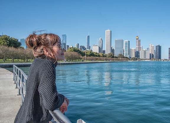 A woman in a black sweater is looking at a city skyline.