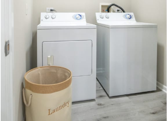a laundry room with two washing machines and a bucket on the floor at Bristol Station, Naperville