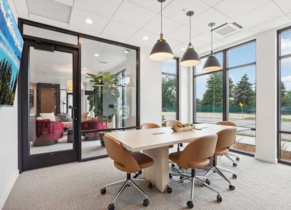 A conference room with a table and chairs and a view of the outside.