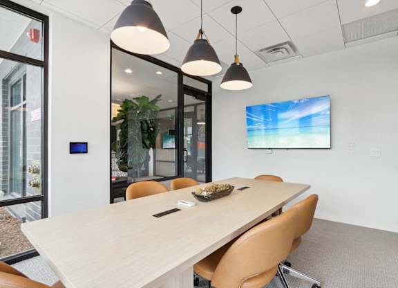A conference room with a long table, chairs, and a television screen on the wall.