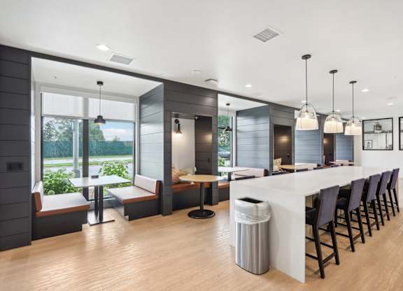 A modern kitchen with a long white island and black bar stools.
