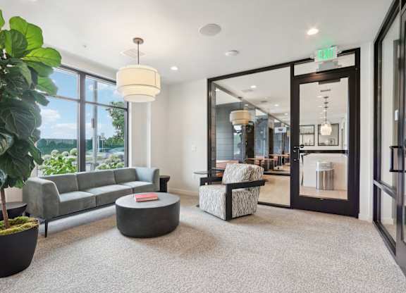A living room with a grey couch, a round coffee table, and a large potted plant.