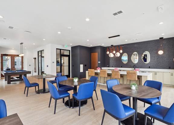 A modern dining room with blue chairs and wooden tables.