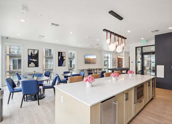 A modern kitchen and dining area with blue chairs and a white counter.