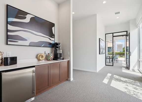 A modern kitchen with a stainless steel refrigerator and a large abstract painting above the counter.