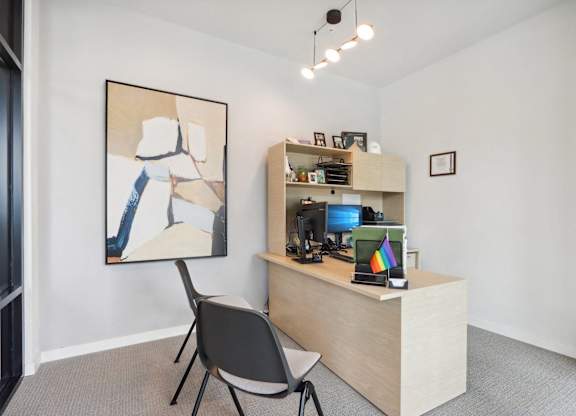 A room with a chair and a painting on the wall.