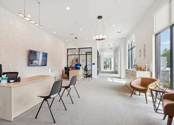 A modern office space with a reception desk and multiple chairs.