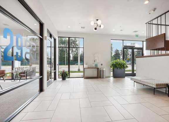 A spacious lobby with a bench, a plant, and a reception desk.