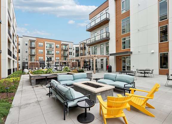A patio with a table and chairs is surrounded by apartment buildings.