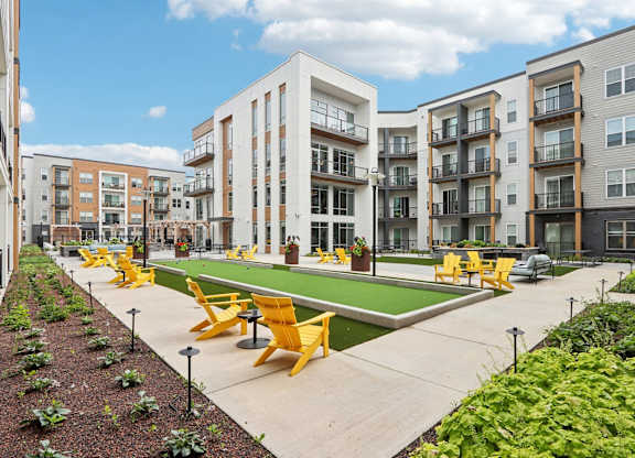 A sunny day at a residential complex with a green lawn and yellow chairs.
