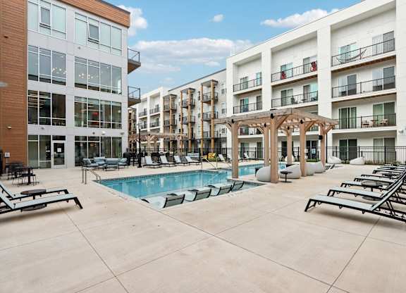 A pool area with sun loungers and a pergola.