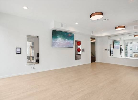 A white room with a painting on the wall and a wooden floor.
