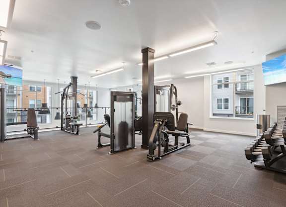 A gym with a variety of equipment including treadmills, weights, and exercise machines.