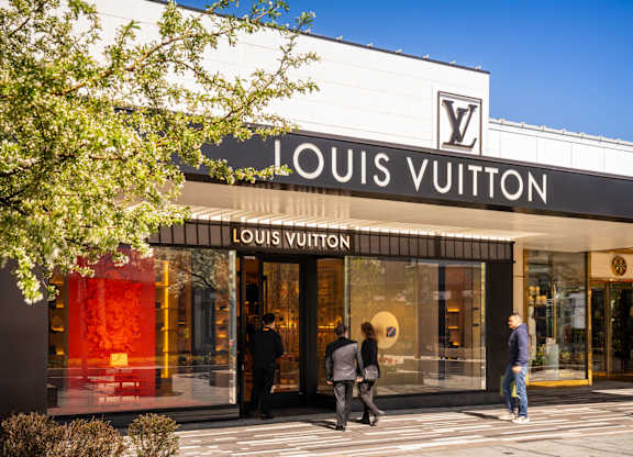A Louis Vuitton store with people walking in front.