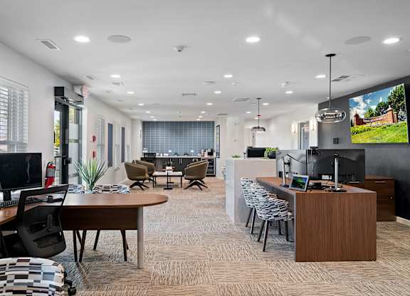 A modern office space with a large desk, chairs, and a TV screen.