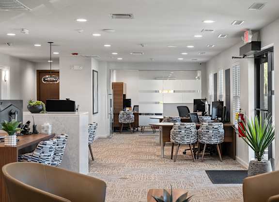 A modern office space with a long table and chairs, a whiteboard, and a plant in a vase.