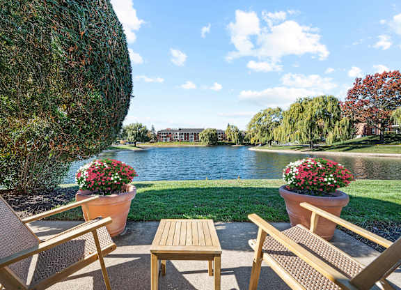 A patio with chairs and a table overlooking a lake.