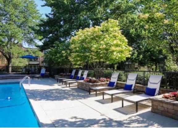 A pool surrounded by trees and chairs at Fieldpointe of Schaumburg, IL, 60173