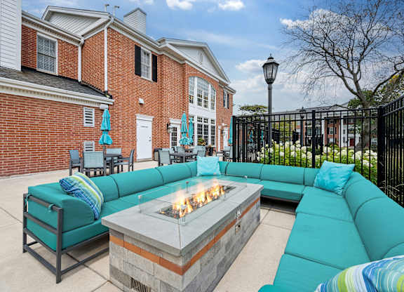 A patio with a fire pit and a blue couch.