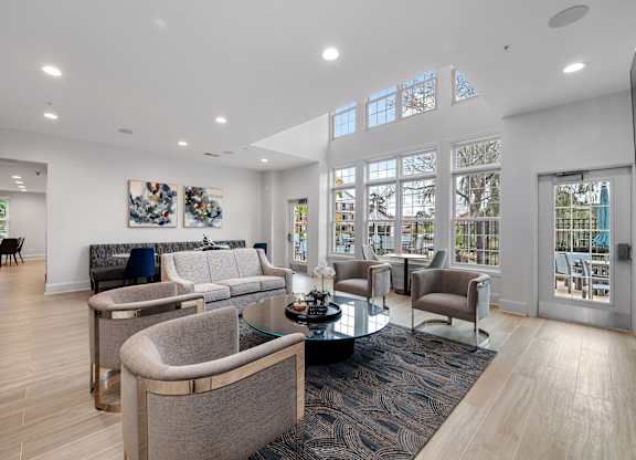 A modern living room with a glass table and grey chairs.