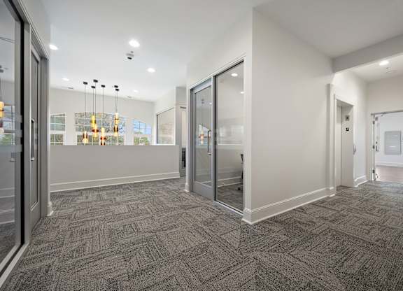 A hallway with a carpeted floor and glass doors.