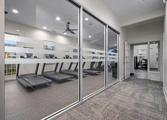 A gym with treadmills and mirrors on the wall.