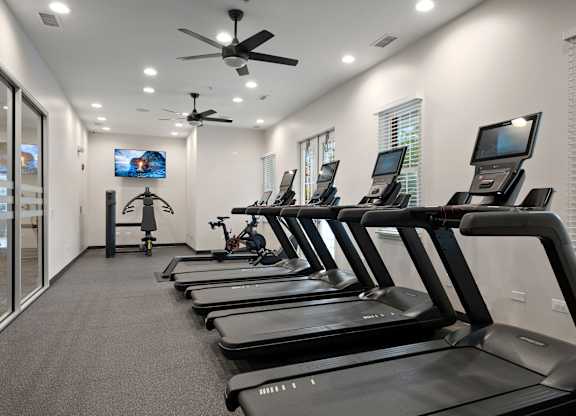 A row of treadmills are lined up in a gym.
