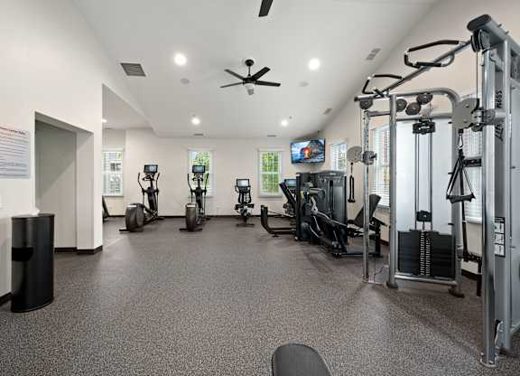 A gym with a variety of equipment including treadmills, weights, and a television.